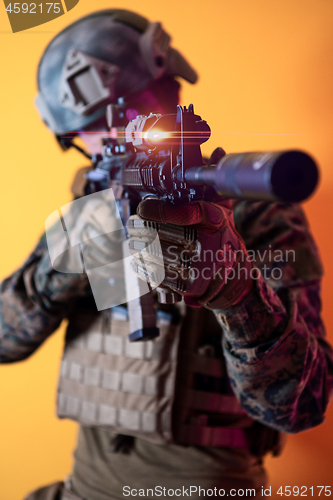 Image of soldier in action aiming laseer sight optics yellow background