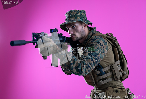 Image of soldier in action aiming laseer sight optics pink background