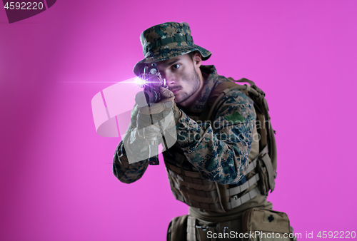 Image of soldier in action aiming laseer sight optics pink background