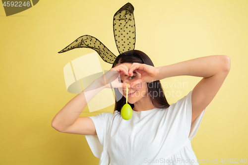 Image of Easter bunny woman with bright emotions on yellow studio background