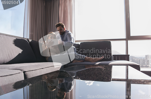 Image of couple relaxing at  home using tablet computer