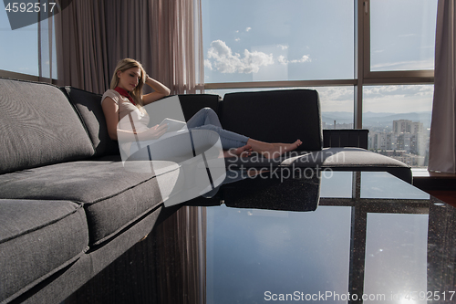 Image of young woman on sofa at home surfing web