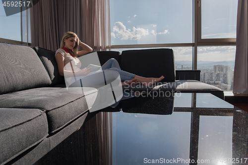 Image of young woman on sofa at home surfing web