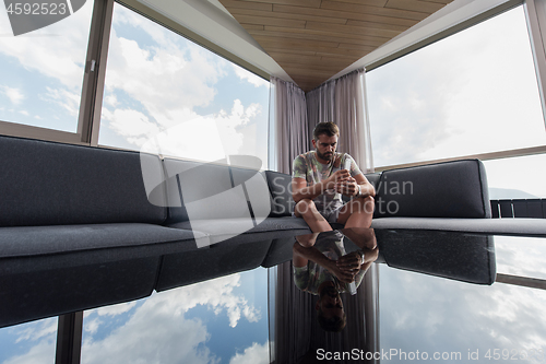 Image of young casual man using a mobile phone at home