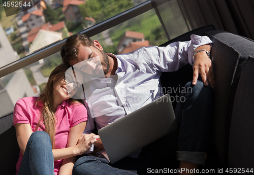 Image of couple relaxing at  home using laptop computers