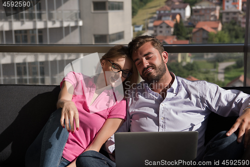 Image of couple relaxing at  home using laptop computers