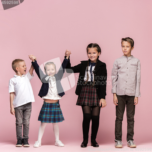 Image of Cute stylish children on pink studio background. The beautiful teen girls and boy standing together