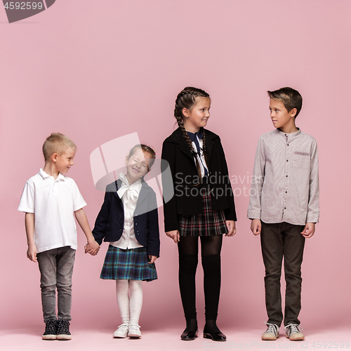 Image of Cute stylish children on pink studio background. The beautiful teen girls and boy standing together