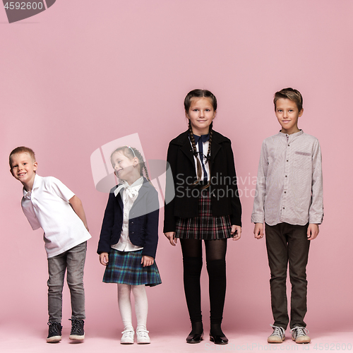 Image of Cute stylish children on pink studio background. The beautiful teen girls and boy standing together