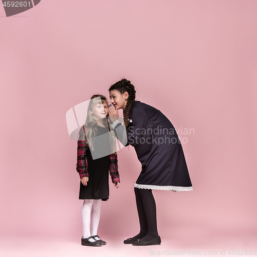 Image of Cute stylish children on pink studio background. The beautiful teen girls standing together