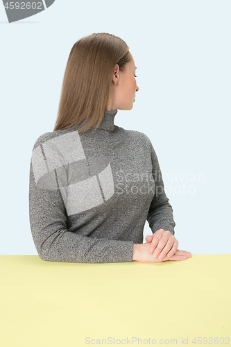 Image of Serious business woman sitting at a table on a pink background