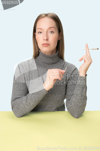 Image of Handsome young women smoking while sitting at table at studio. Trendy colors