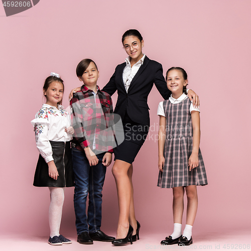 Image of Cute stylish children on pink studio background. The beautiful teen girls and boy standing together