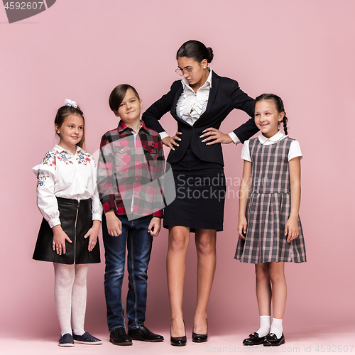 Image of Cute stylish children on pink studio background. The beautiful teen girls and boy standing together