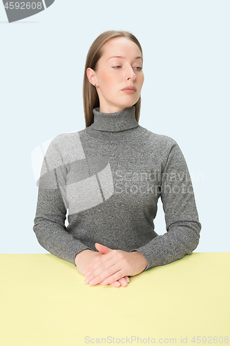 Image of Serious business woman sitting at a table on a pink background