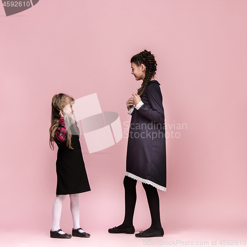 Image of Cute stylish children on pink studio background. The beautiful teen girls standing together