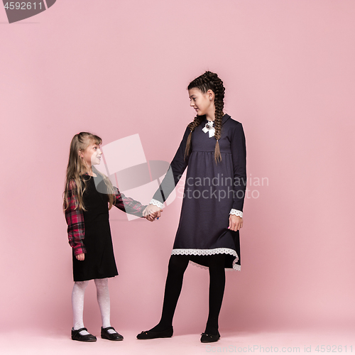 Image of Cute stylish children on pink studio background. The beautiful teen girls standing together