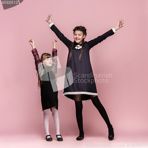 Image of Cute stylish children on pink studio background. The beautiful teen girls standing together
