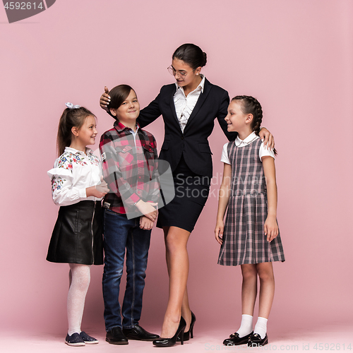 Image of Cute stylish children on pink studio background. The beautiful teen girls and boy standing together