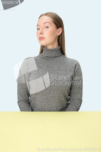 Image of Serious business woman sitting at a table on a pink background