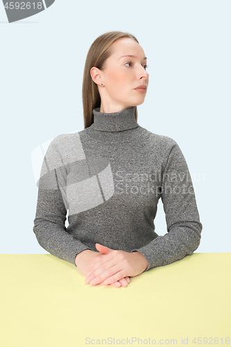 Image of Serious business woman sitting at a table on a pink background