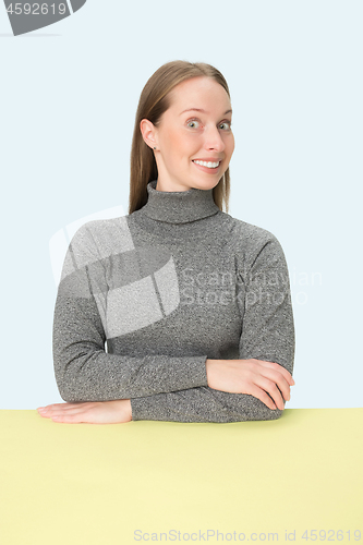 Image of The happy and smiling business woman sitting at a table on a pink background