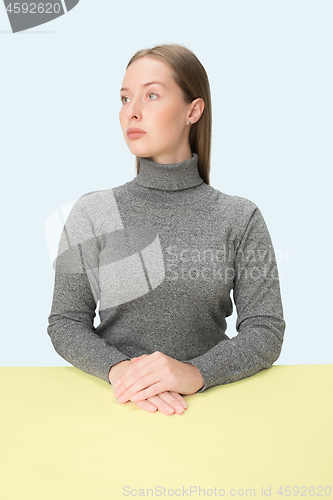 Image of Serious business woman sitting at a table on a pink background