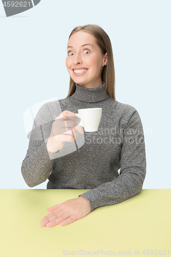 Image of Beautiful lonely woman sitting at studio and looking sad holding the cup of coffee in hand. Closeup toned portrait