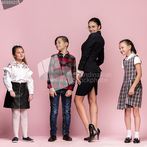 Image of Cute stylish children on pink studio background. The beautiful teen girls and boy standing together