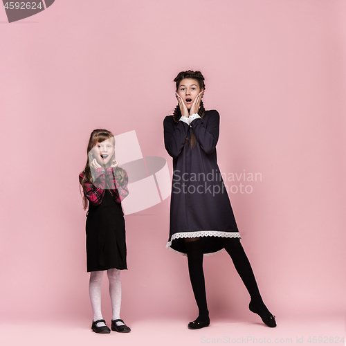 Image of Cute stylish children on pink studio background. The beautiful teen girls standing together