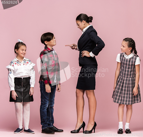 Image of Cute stylish children on pink studio background. The beautiful teen girls and boy standing together
