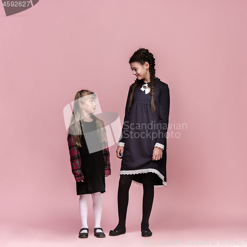 Image of Cute stylish children on pink studio background. The beautiful teen girls standing together