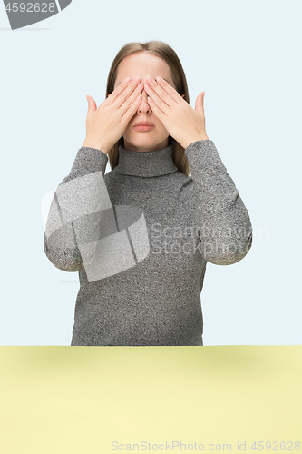 Image of Young woman sitting at table at studio with eyes closed isolated on blue