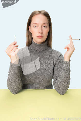 Image of Handsome young women smoking while sitting at table at studio. Trendy colors