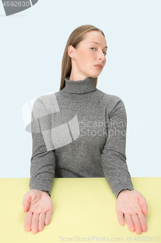 Image of Serious business woman sitting at a table on a pink background