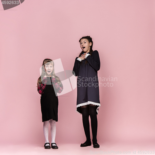 Image of Cute stylish children on pink studio background. The beautiful teen girls standing together