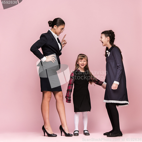 Image of Cute stylish children on pink studio background. The beautiful teen girls standing together