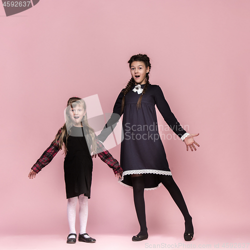 Image of Cute stylish children on pink studio background. The beautiful teen girls standing together