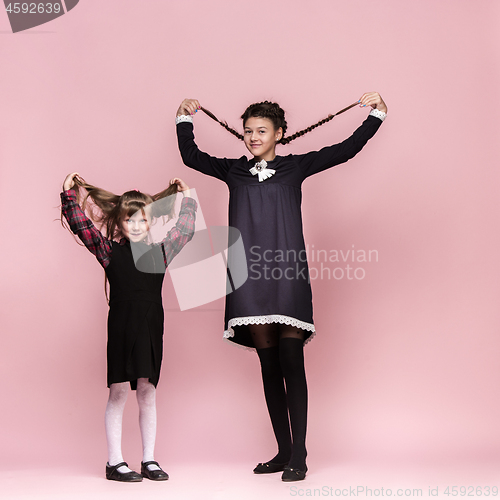 Image of Cute stylish children on pink studio background. The beautiful teen girls standing together