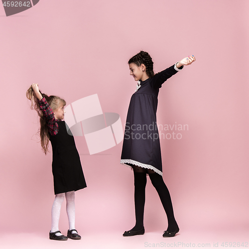 Image of Cute stylish children on pink studio background. The beautiful teen girls standing together