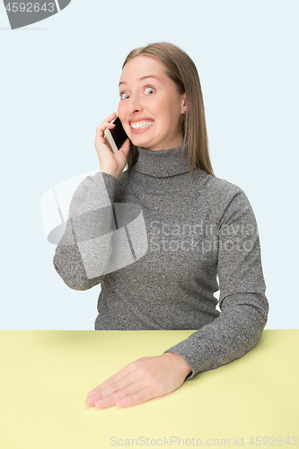 Image of The happy business woman sitting with mobile phone against pink background.