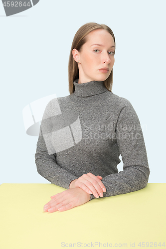 Image of Serious business woman sitting at a table on a pink background