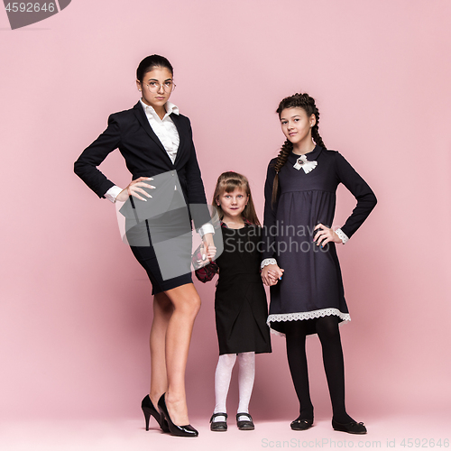 Image of Cute stylish children on pink studio background. The beautiful teen girls standing together