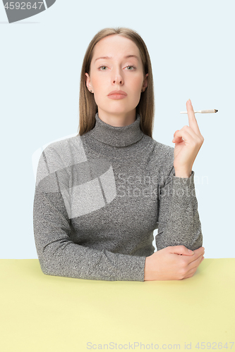 Image of Handsome young women smoking while sitting at table at studio. Trendy colors