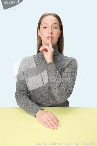 Image of Shhhhh . Beautiful girl with bright makeup and curly hair telling a secret .