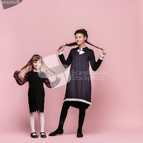 Image of Cute stylish children on pink studio background. The beautiful teen girls standing together