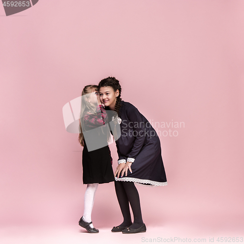Image of Cute stylish children on pink studio background. The beautiful teen girls standing together