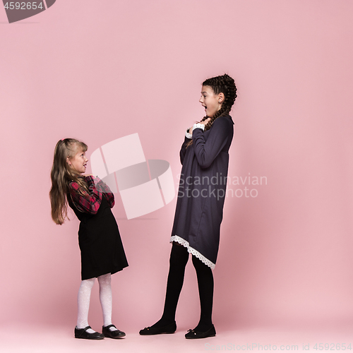 Image of Cute stylish children on pink studio background. The beautiful teen girls standing together