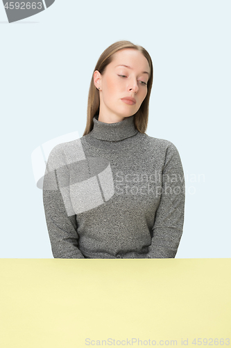 Image of Serious business woman sitting at a table on a pink background