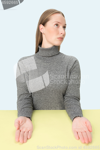 Image of Serious business woman sitting at a table on a pink background